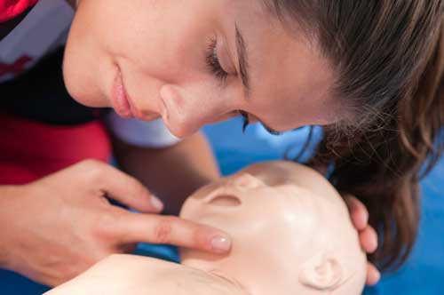 Person utför hjärt och lungräddning på en spädbarns docka